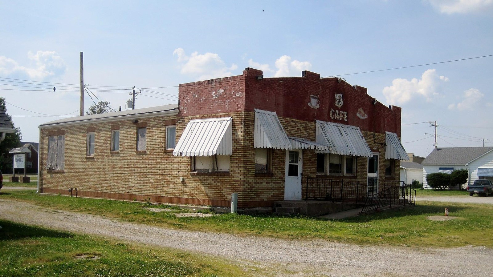 A red brick building with white fabric awnings, surrounded by grass.