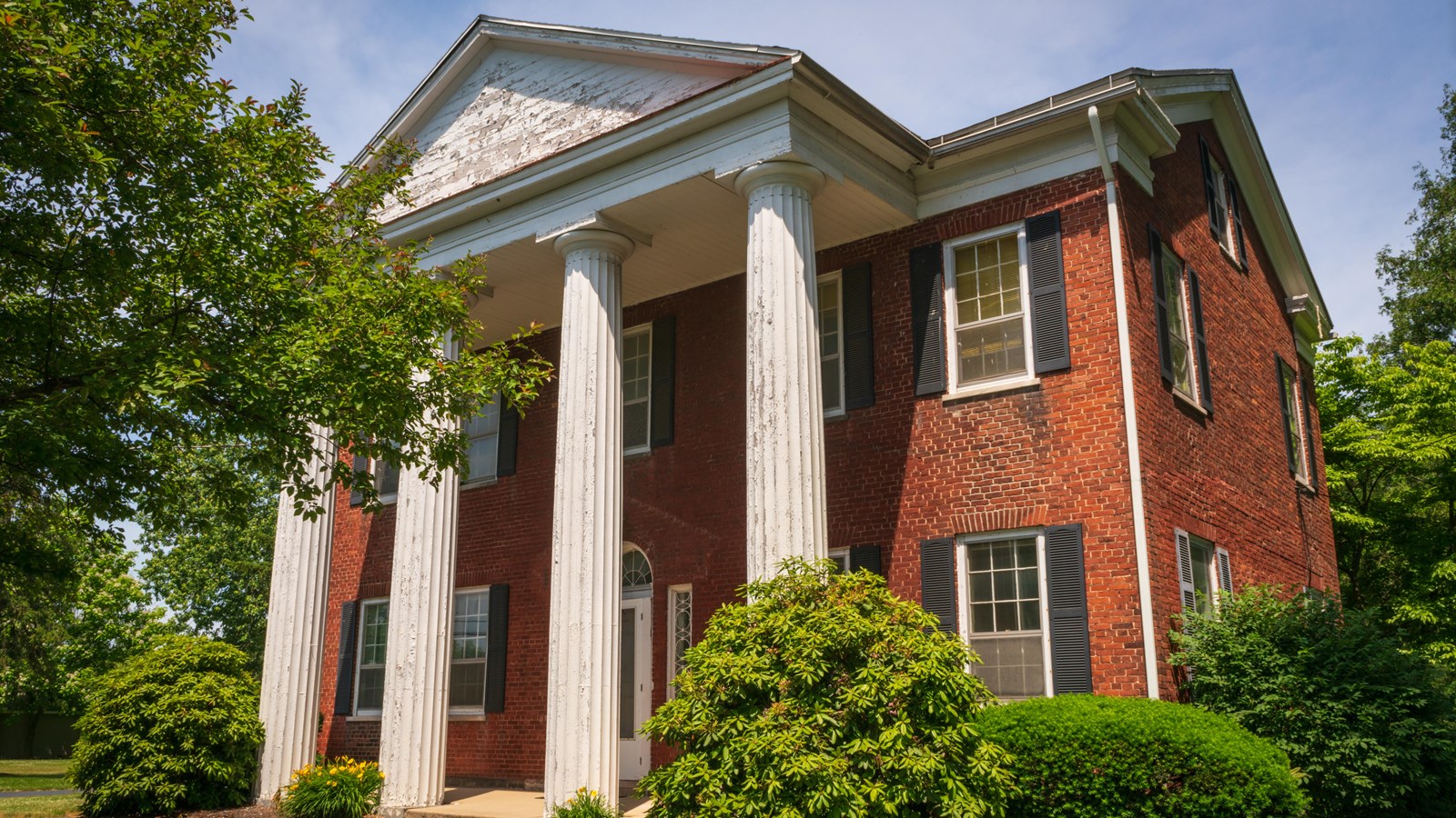 A large, two-story brick house with a tall white portico and four columns.