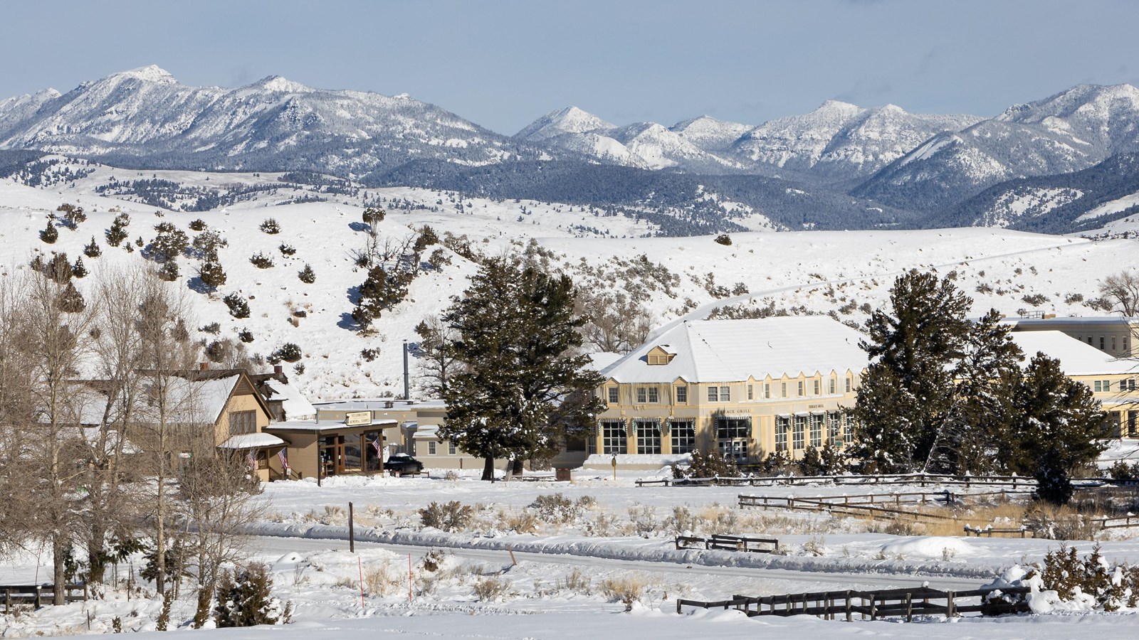 Two large buildings stand in front of a mountain in the snow.