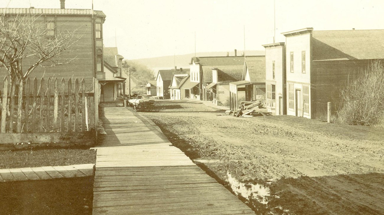Old buildings with a dirt road and wooden boardwalks.