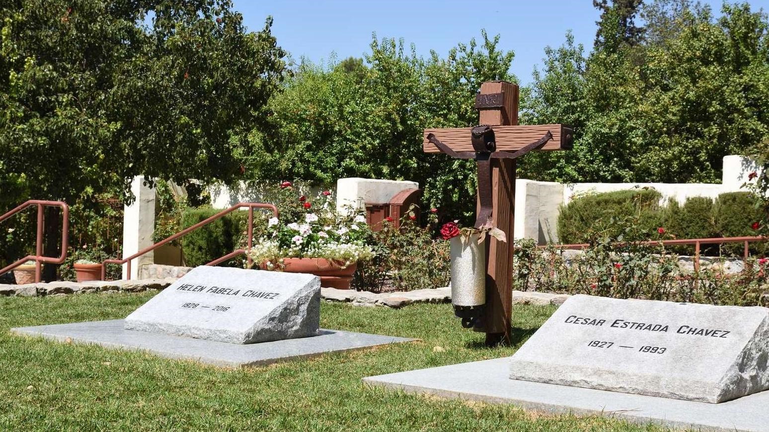 Between two graves is a rustic wooden cross with a human figure attached in iron.