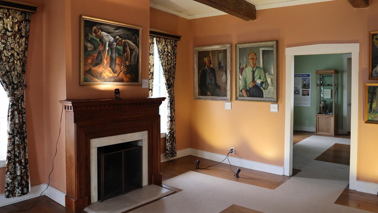 A room filled with paintings hanging on the walls and a fireplace. 