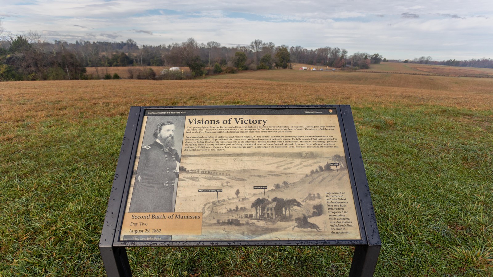 An informational panel in front of a grassy field.