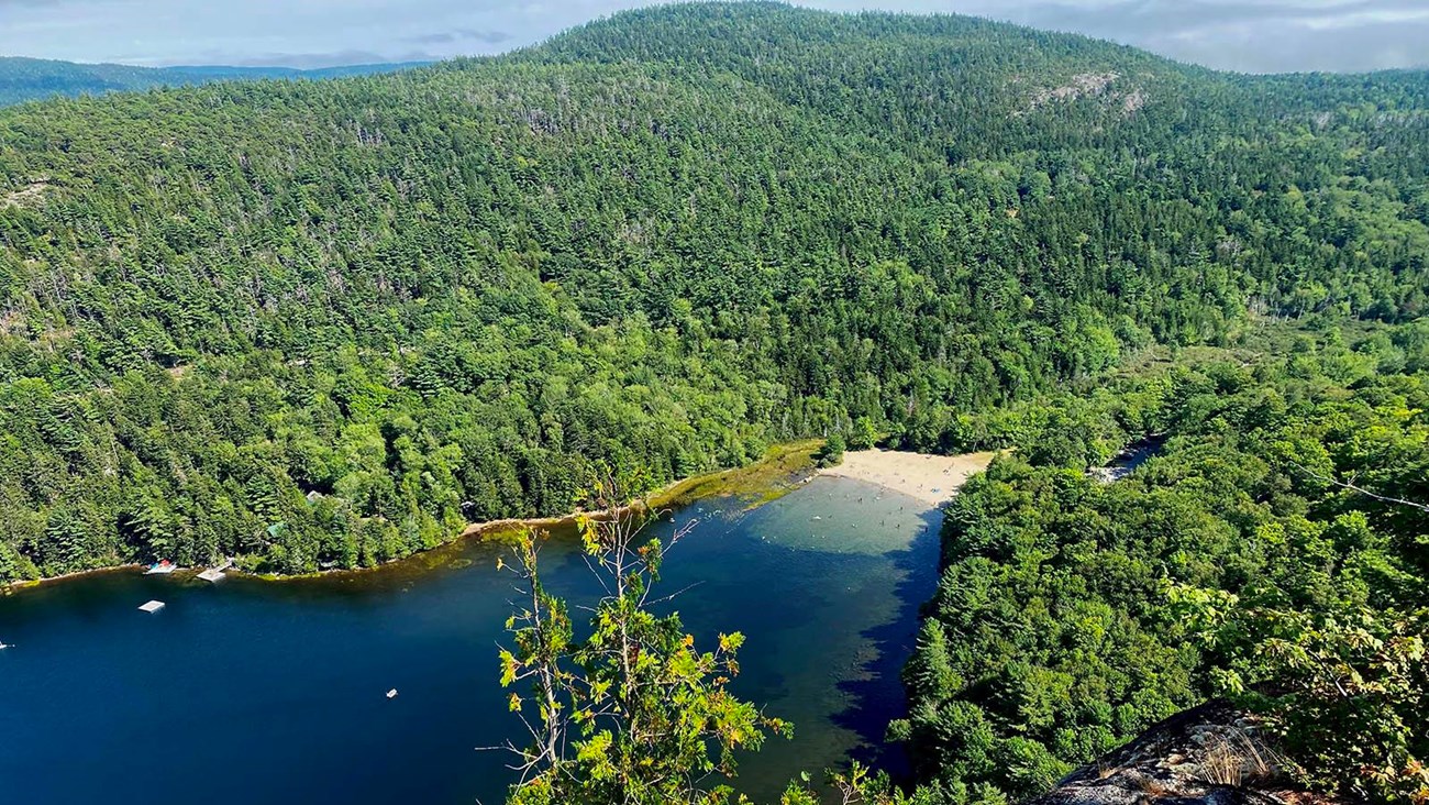 Echo Lake and Beach are nestled at the bottom a mountain ridge while granite cliffs rise steeply.