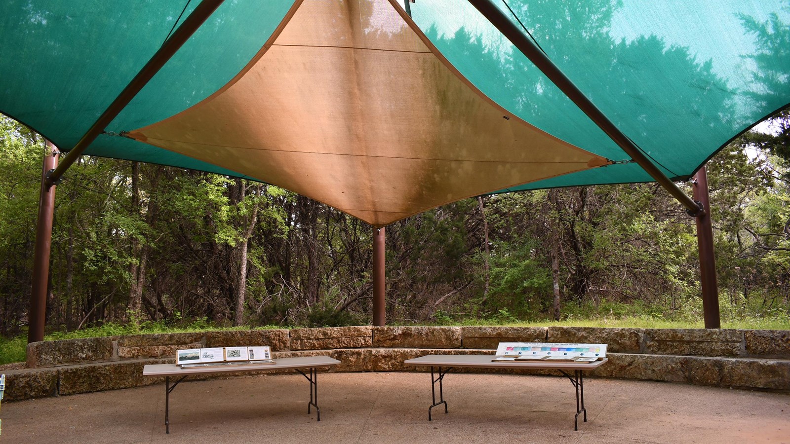 A circle of benches is shaded by a cloth tarp.