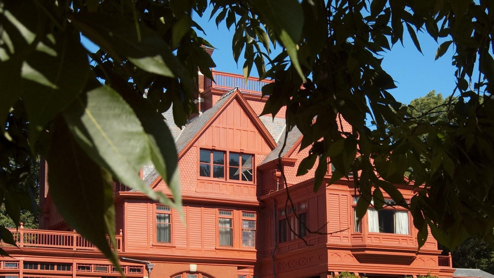 Red brick colored home on an expansive green lawn with trees