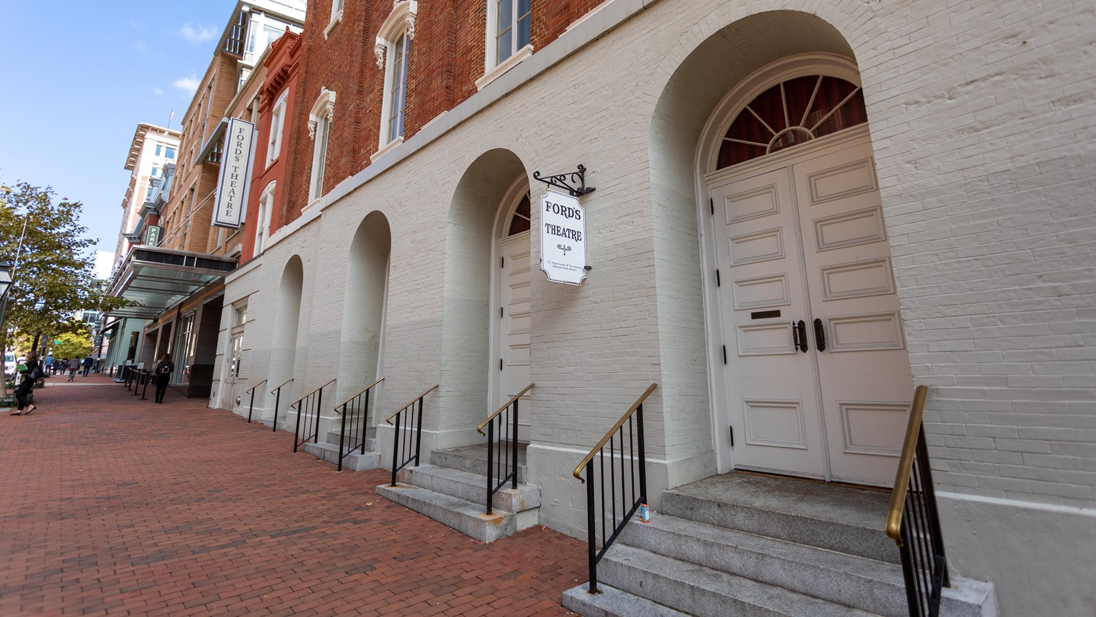 Arched doorways and white brick exterior of the theatre entrance.
