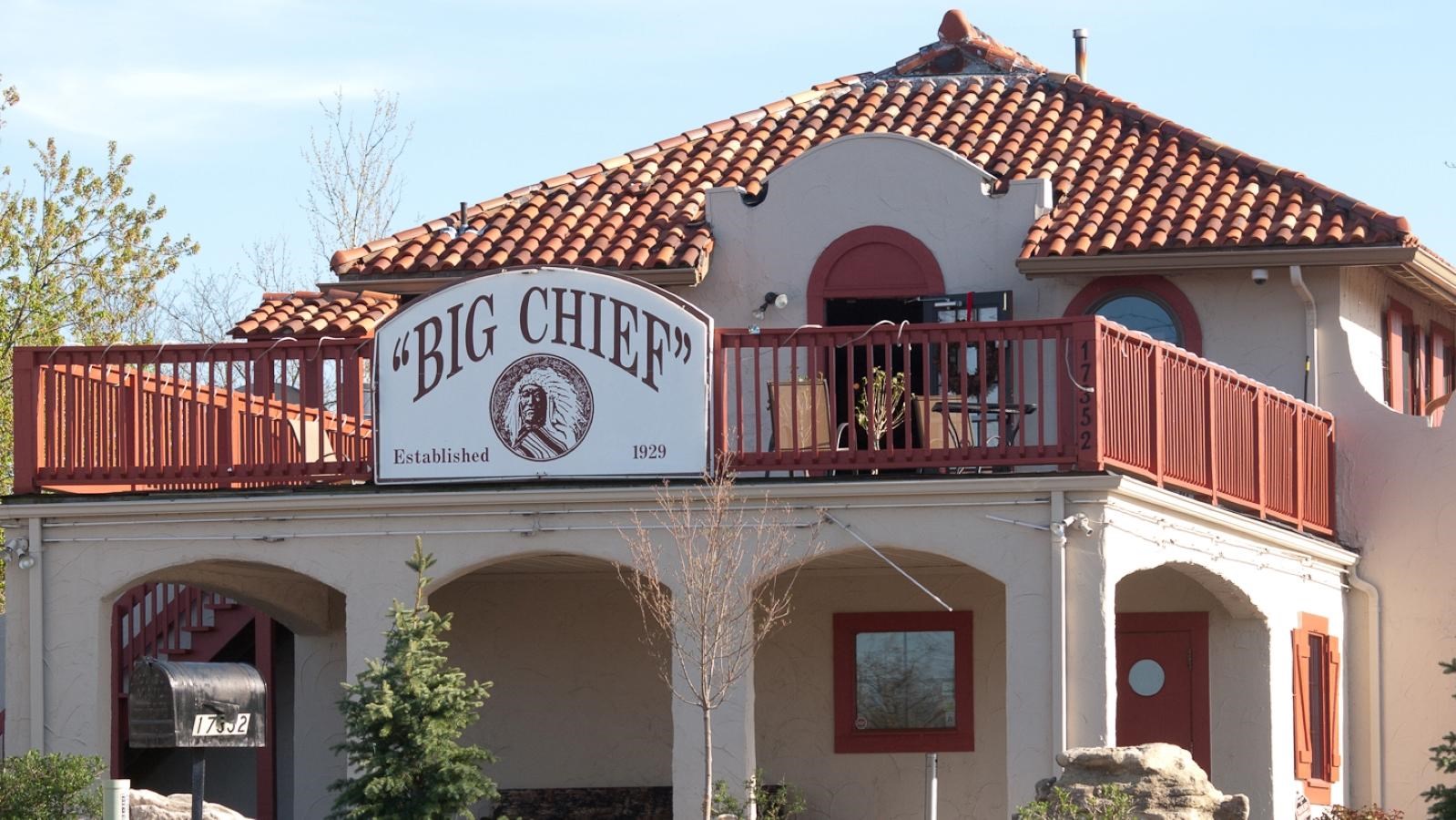 A two story white stucco building with terracotta trim. A sign reads 
