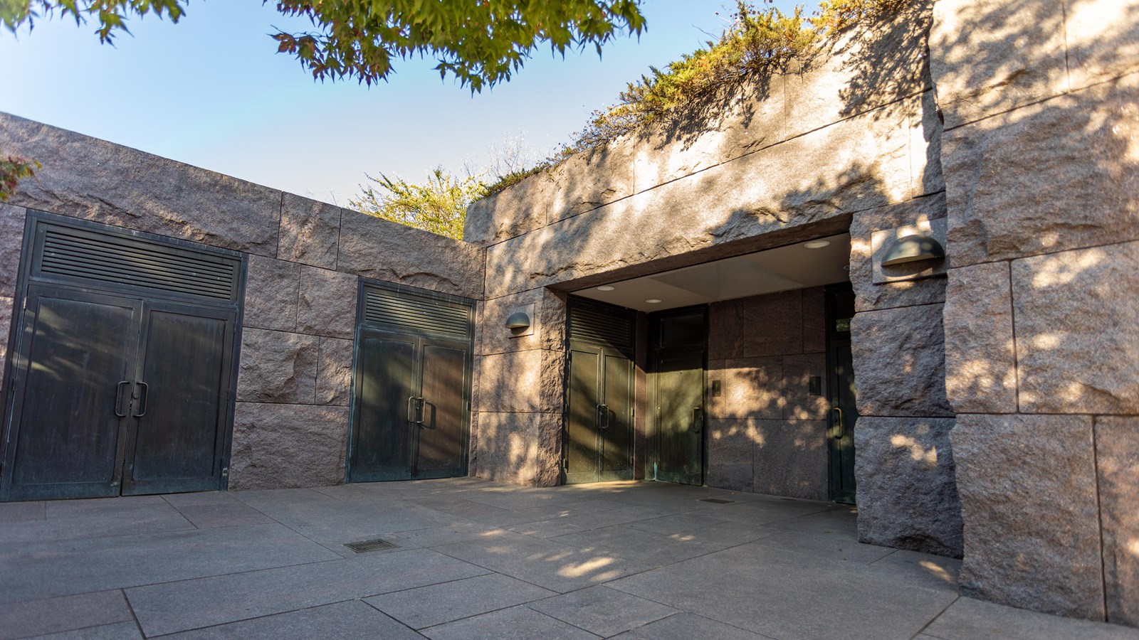 Bronze doors recessed into a granite wall.