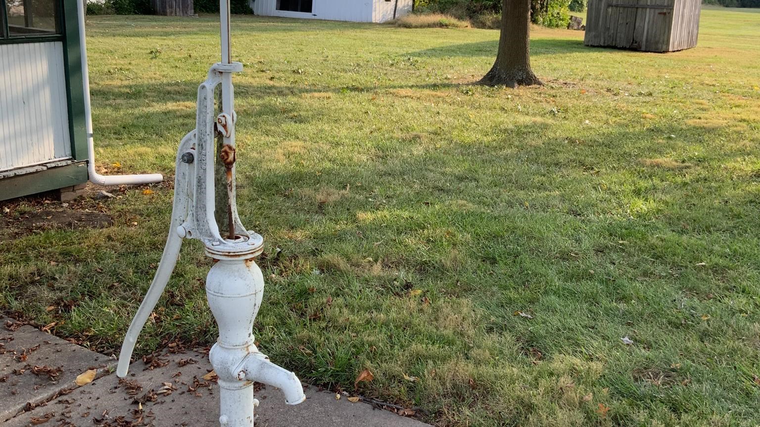 In the foreground the white water pump, in the background the Truman home, chicken coop, and yard.