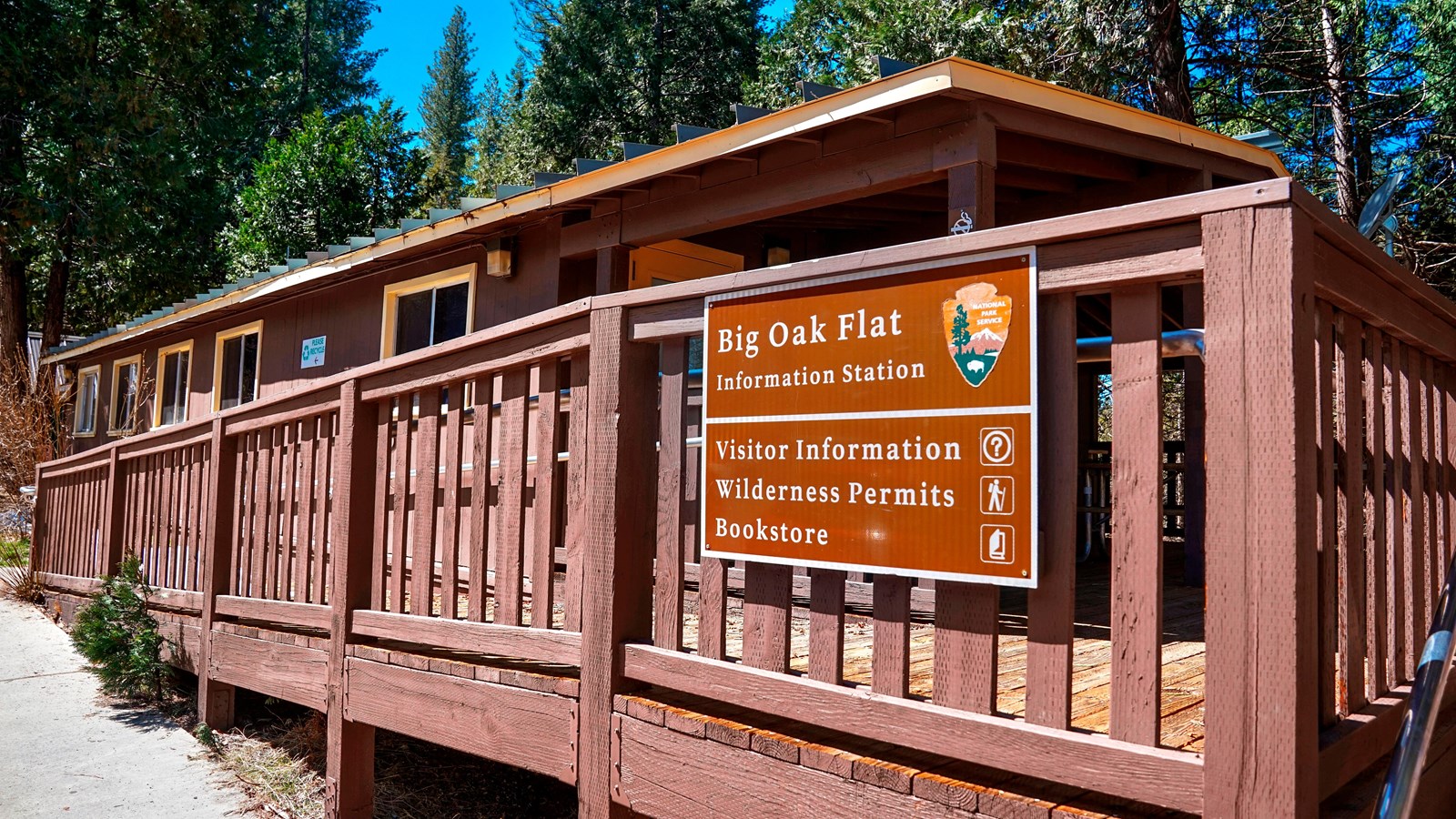 A low brown building with a wood porch, a sign reads 