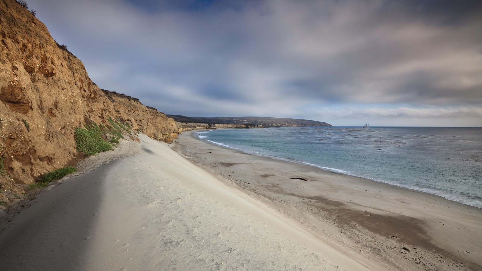 White sand beach with sand dunes and aqua ocean.