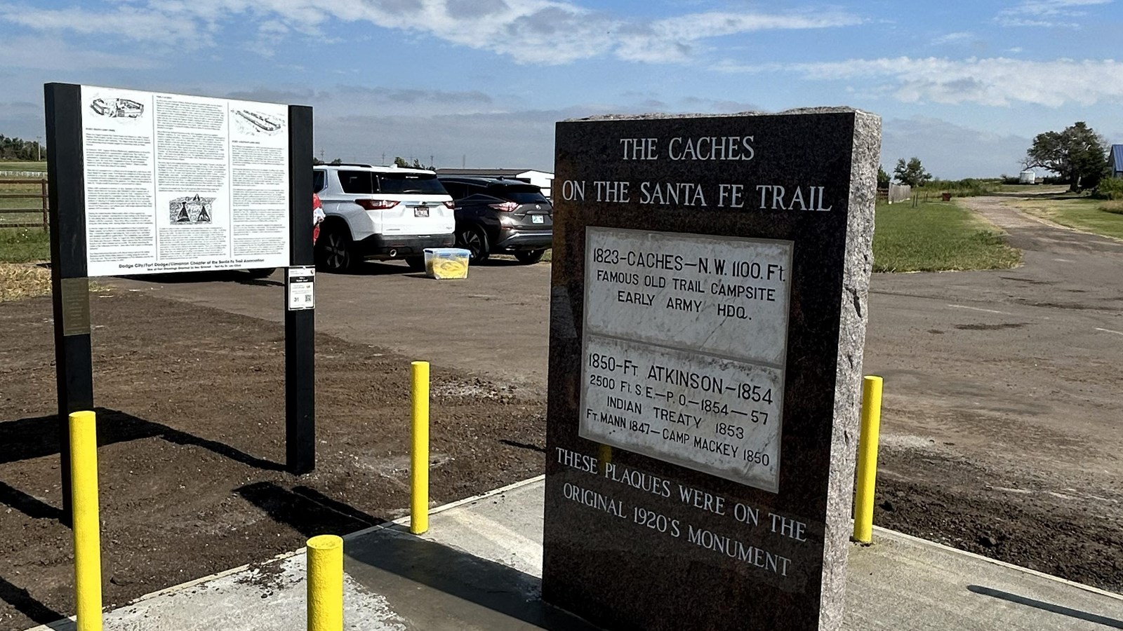 A large stone marker with a plaque in a field.