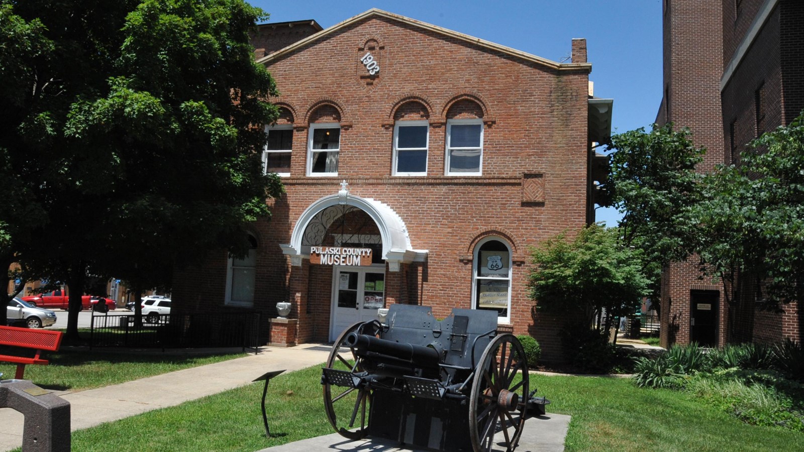 A two story red brick building with arched windows. A sign reads