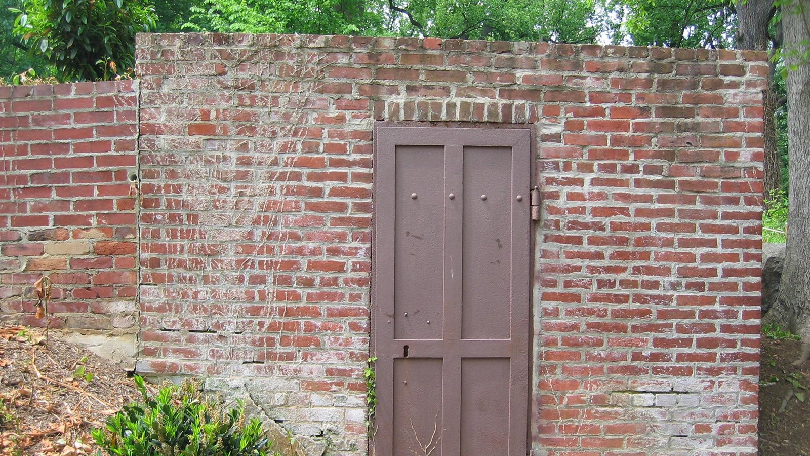A plain brick wall with a brown metal door