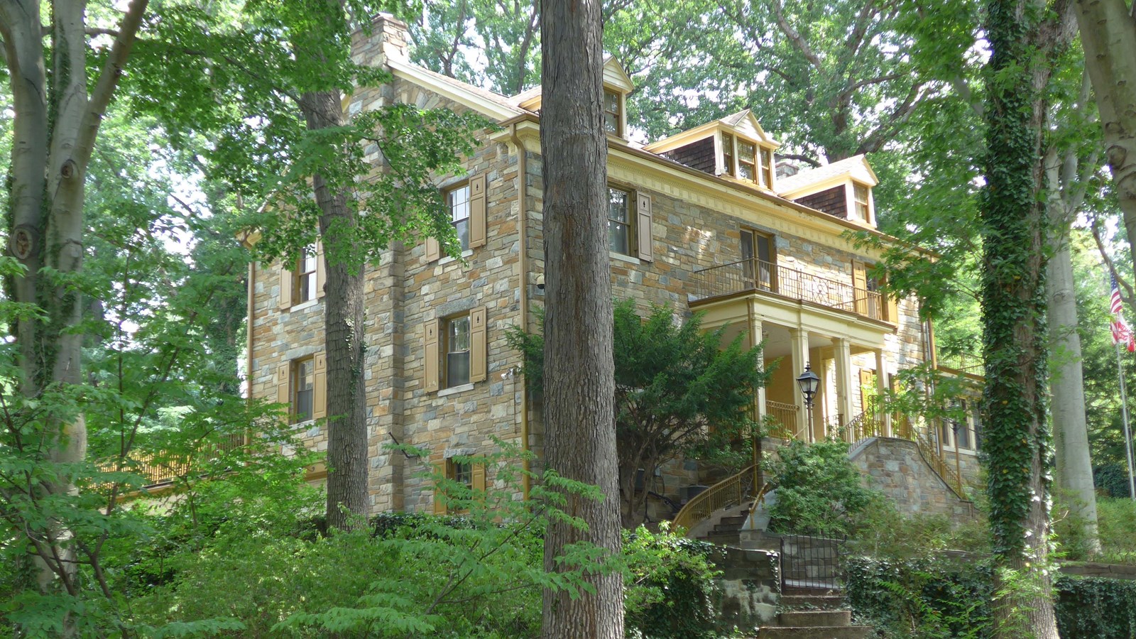 three-story stone house with a covered porch and steps leading to the second level entrance 