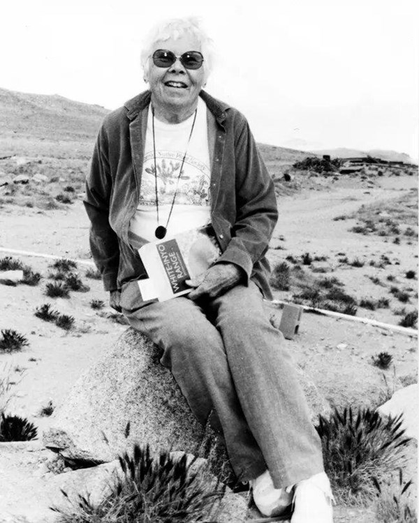 Woman sits on a rock in the desert. 