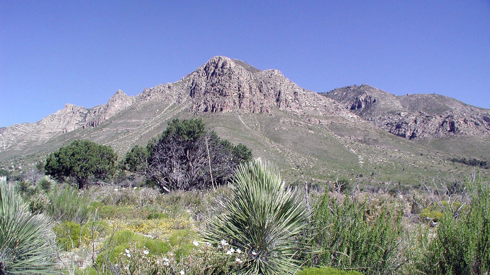A large peak rises above a desert mountain landscape