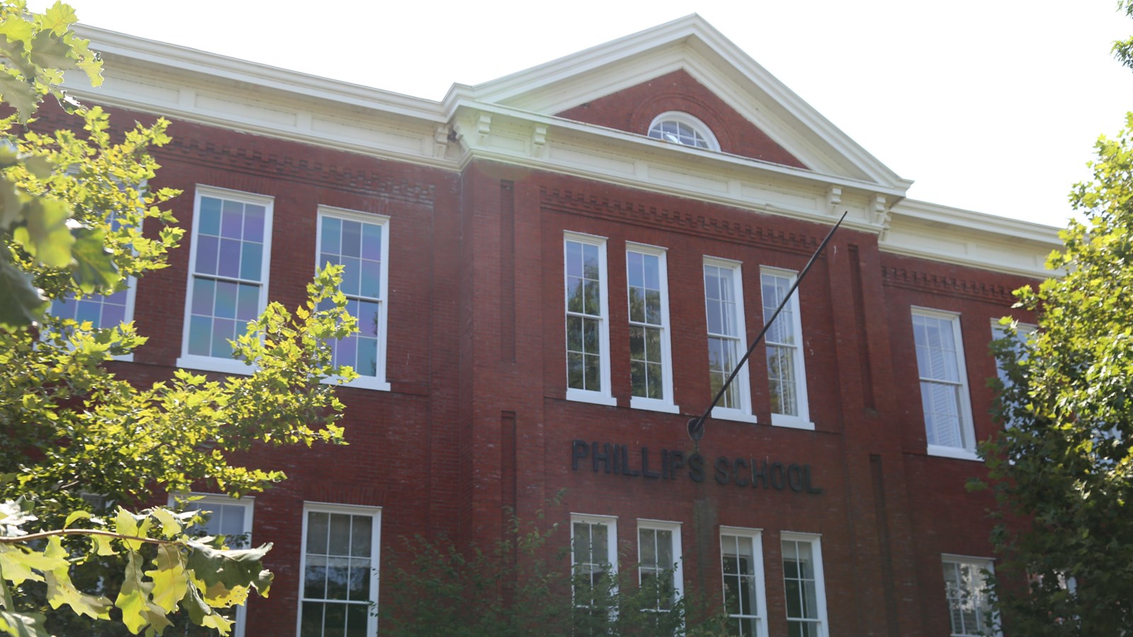 A brick building with large windows. A flag pole juts out below the second floor middle window.