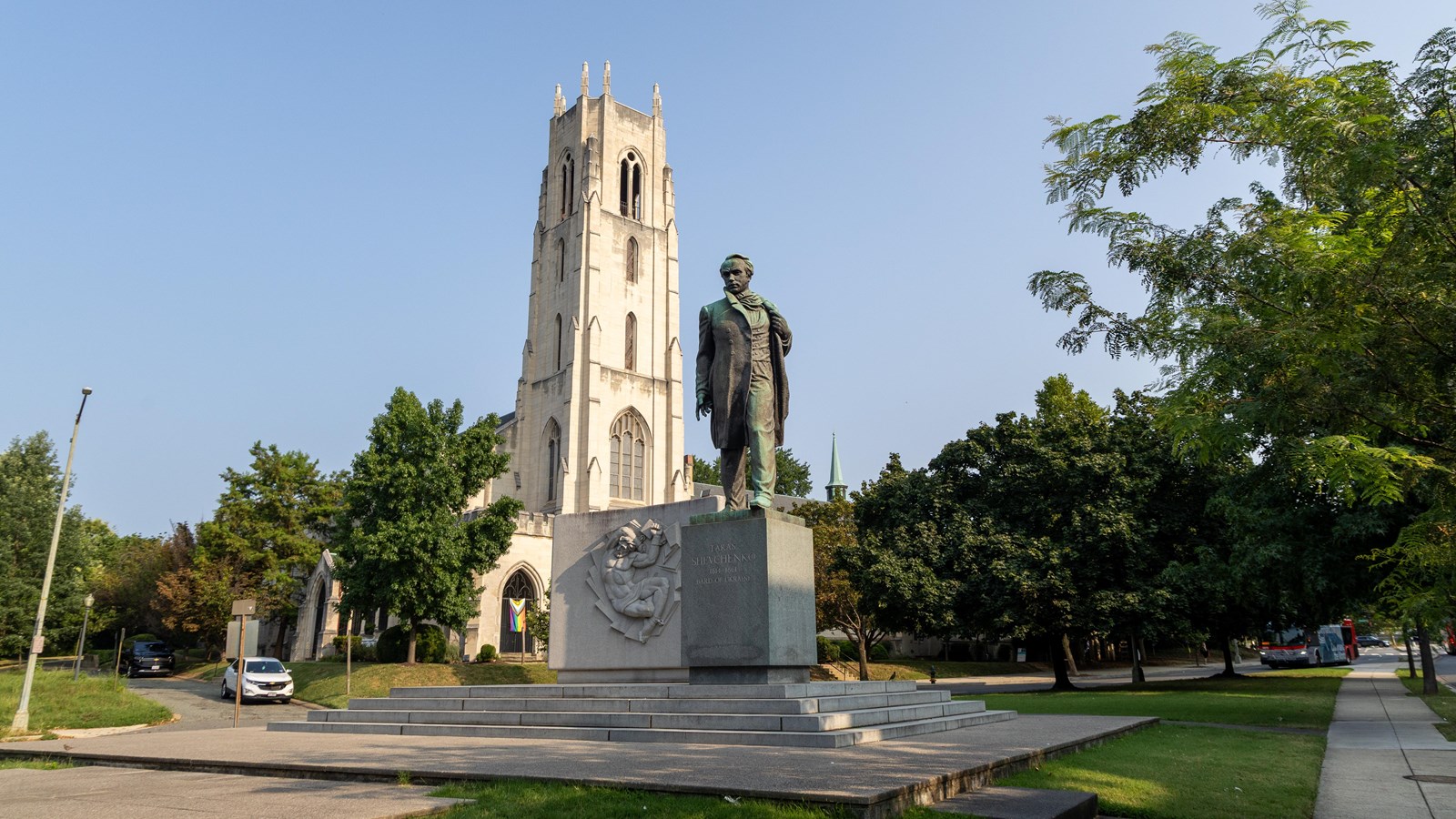 A statue of a man in a long coat with a church behind him