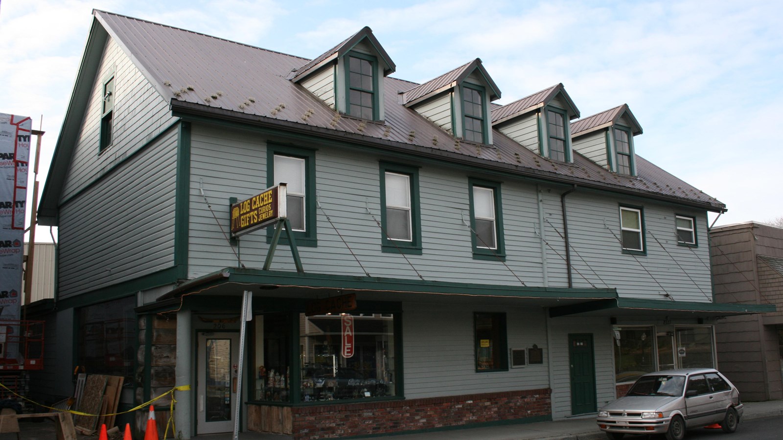 A two story gray building with green trim, gable roof, and four dormer windows.