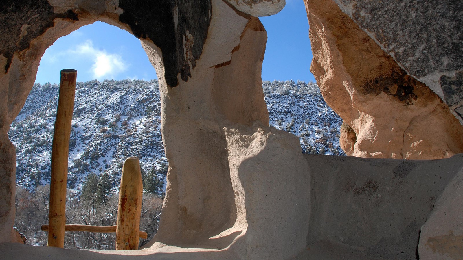 a ladder leans against an opening in a rock wall, 2nd opening is to the right showing a snow cliff