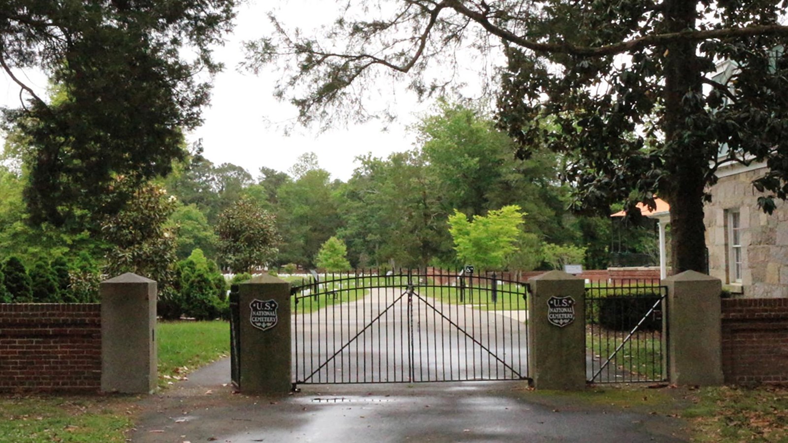 Two iron gates with granite posts and a wall of red brick with Ohio sandstone. 