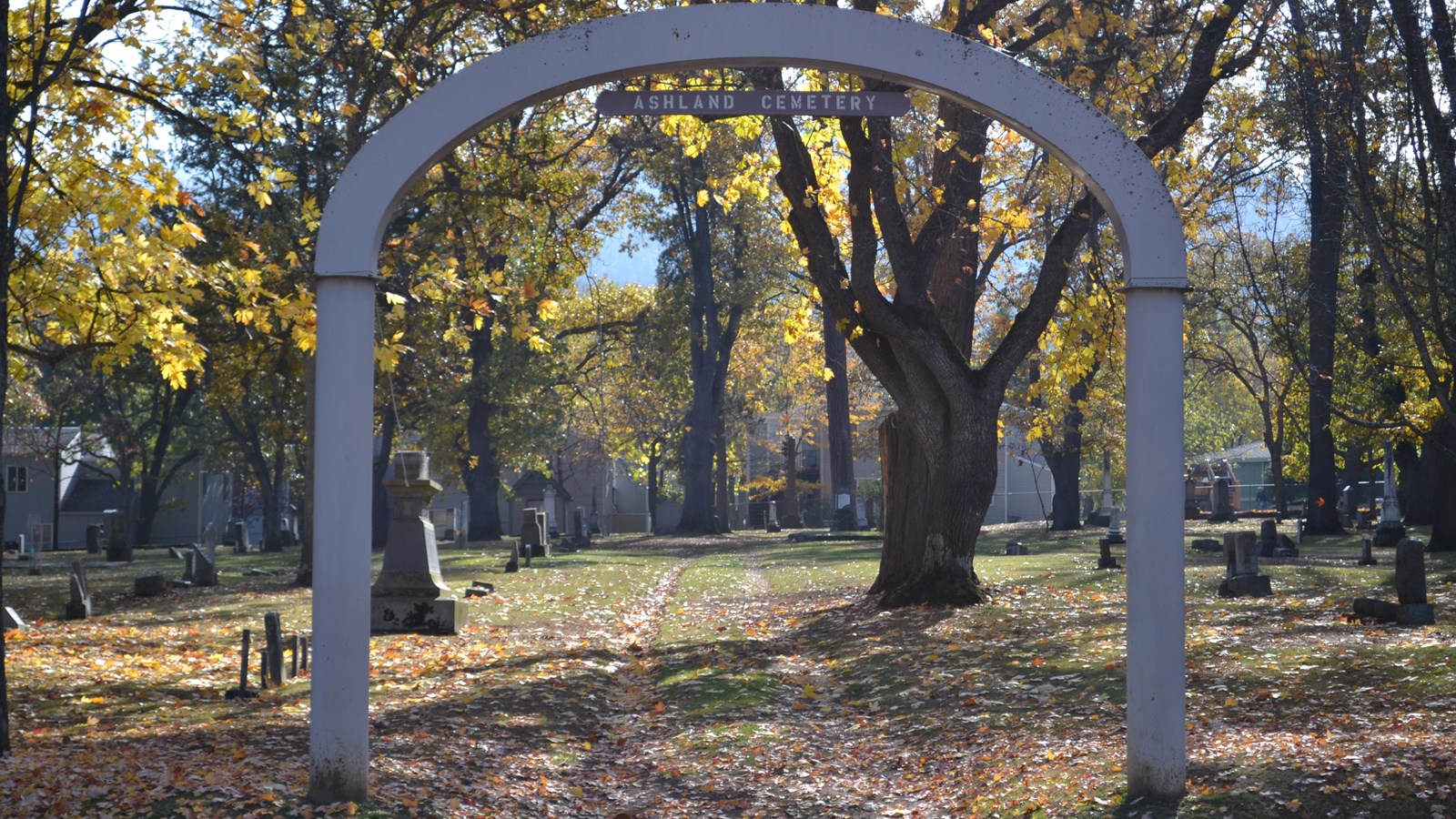 Cemetery headstone visible under large stone arch. 