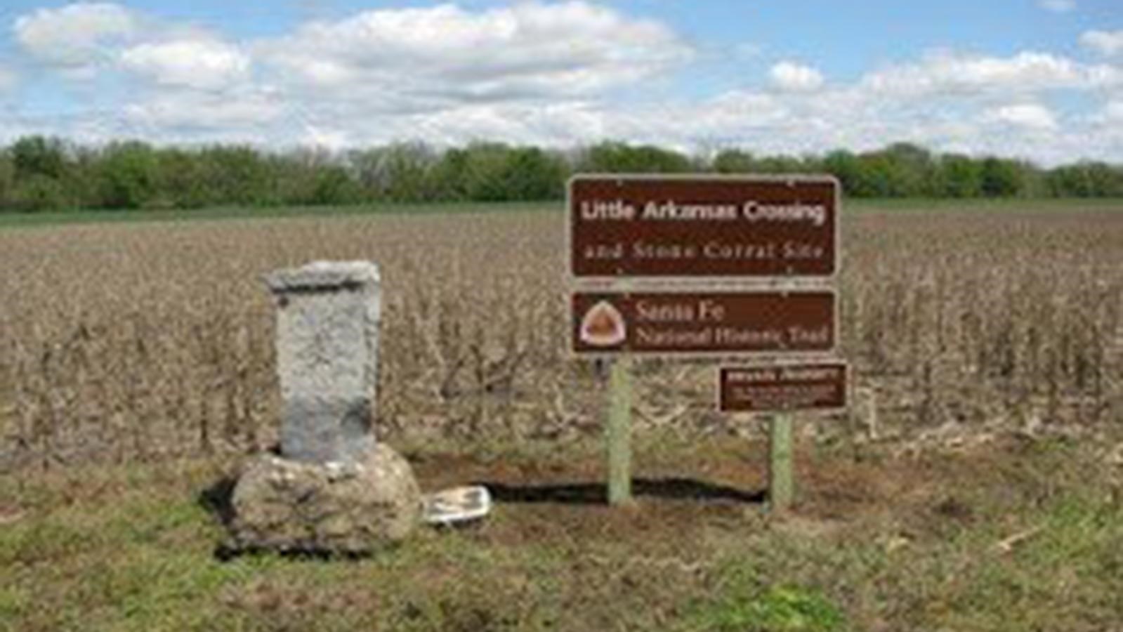 Stone marker and metal sign in a grassy pasture