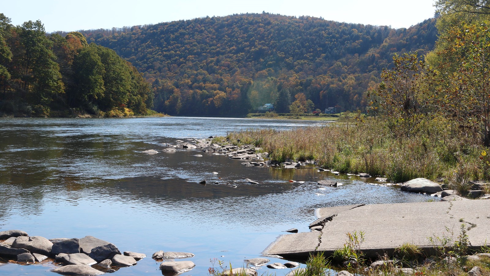 River access. In foreground is cracked pavement ramp and rocks into the water. In background, hills.