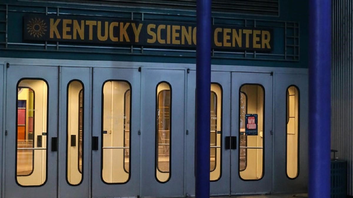 Silver doors with Kentucky Science Center written above them under a blue-columned porch