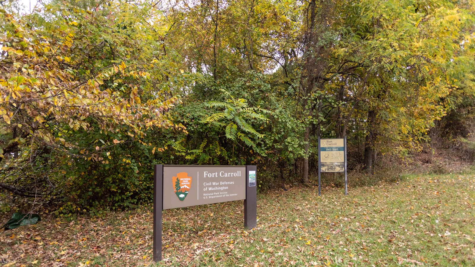 A large NPS sign in front of a wooded area.