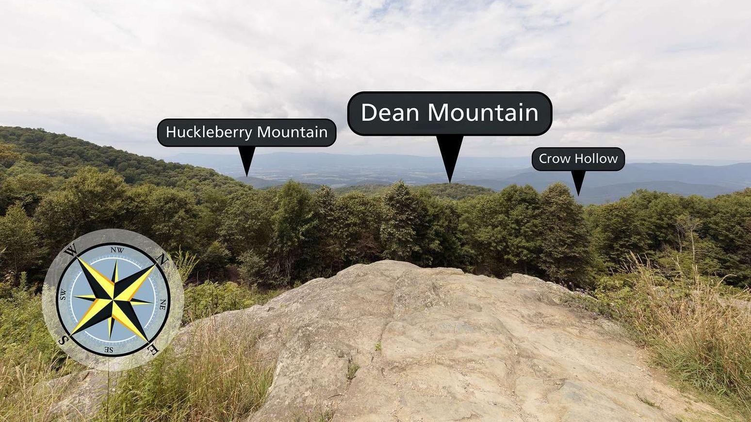 View over rock ledge into forest with valley below.