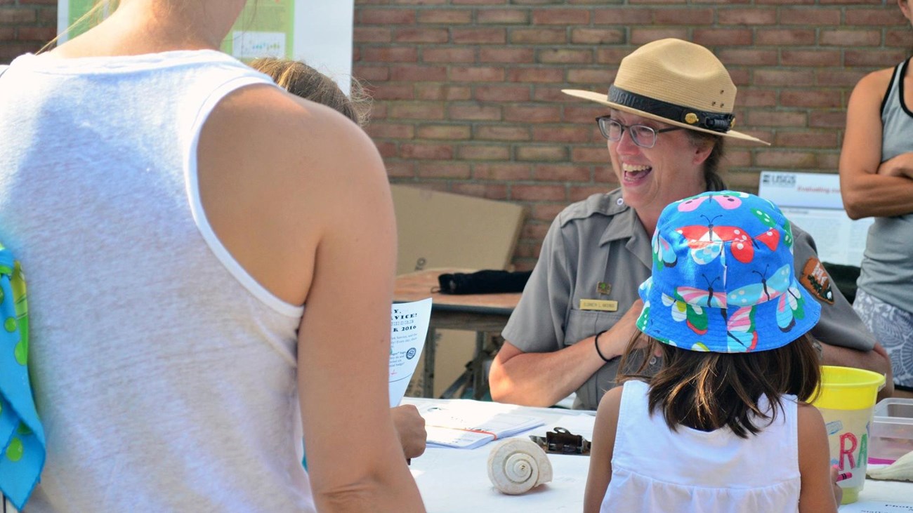 Park ranger gives out Junior Ranger badge to young visitor.