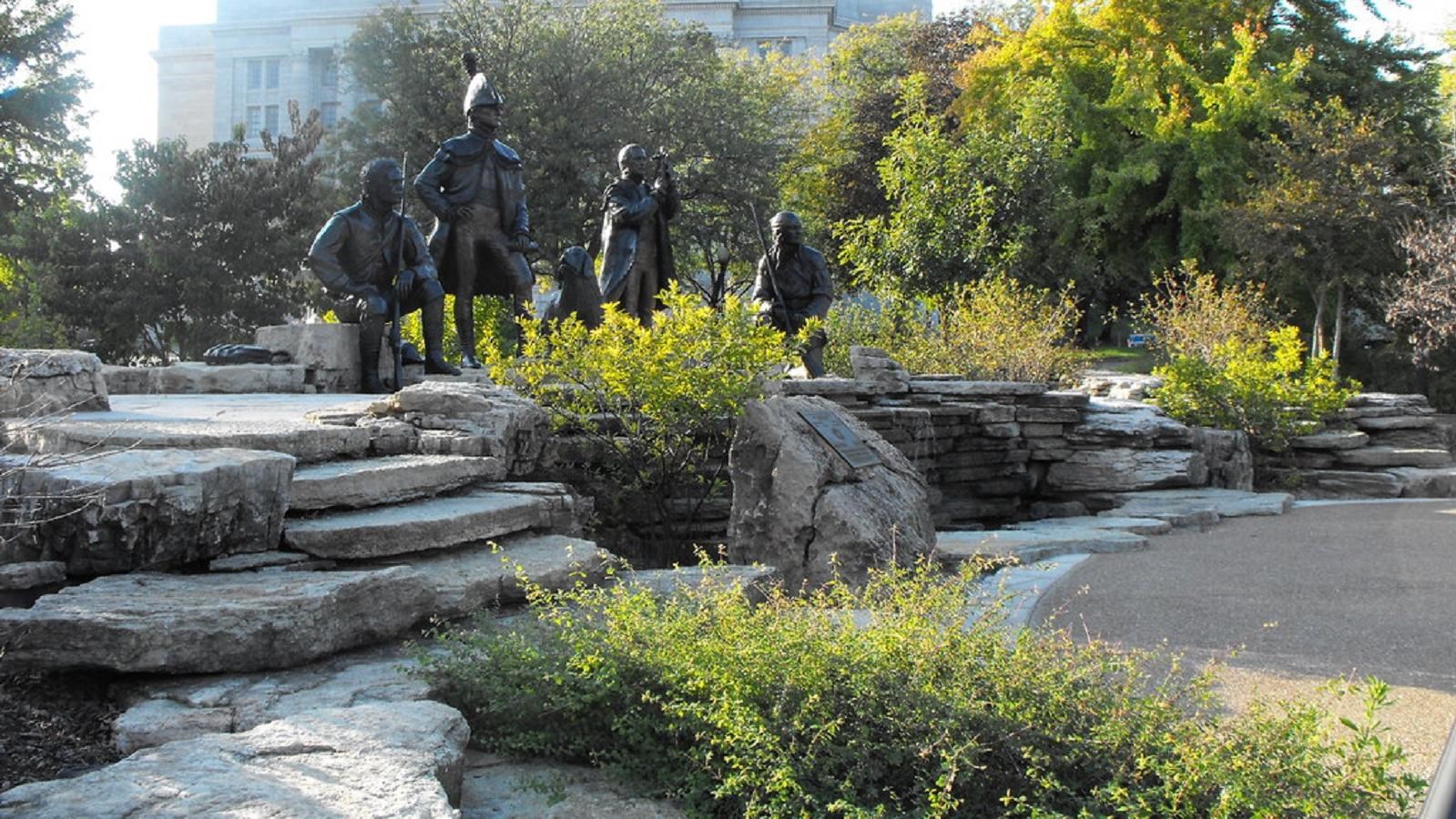 Five bronze statues of a waterfall feature made of stacked sandstone shale