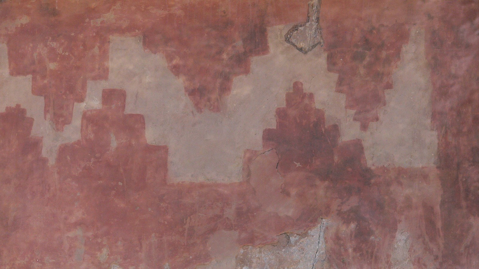 a red and beige geometric design on a rock wall