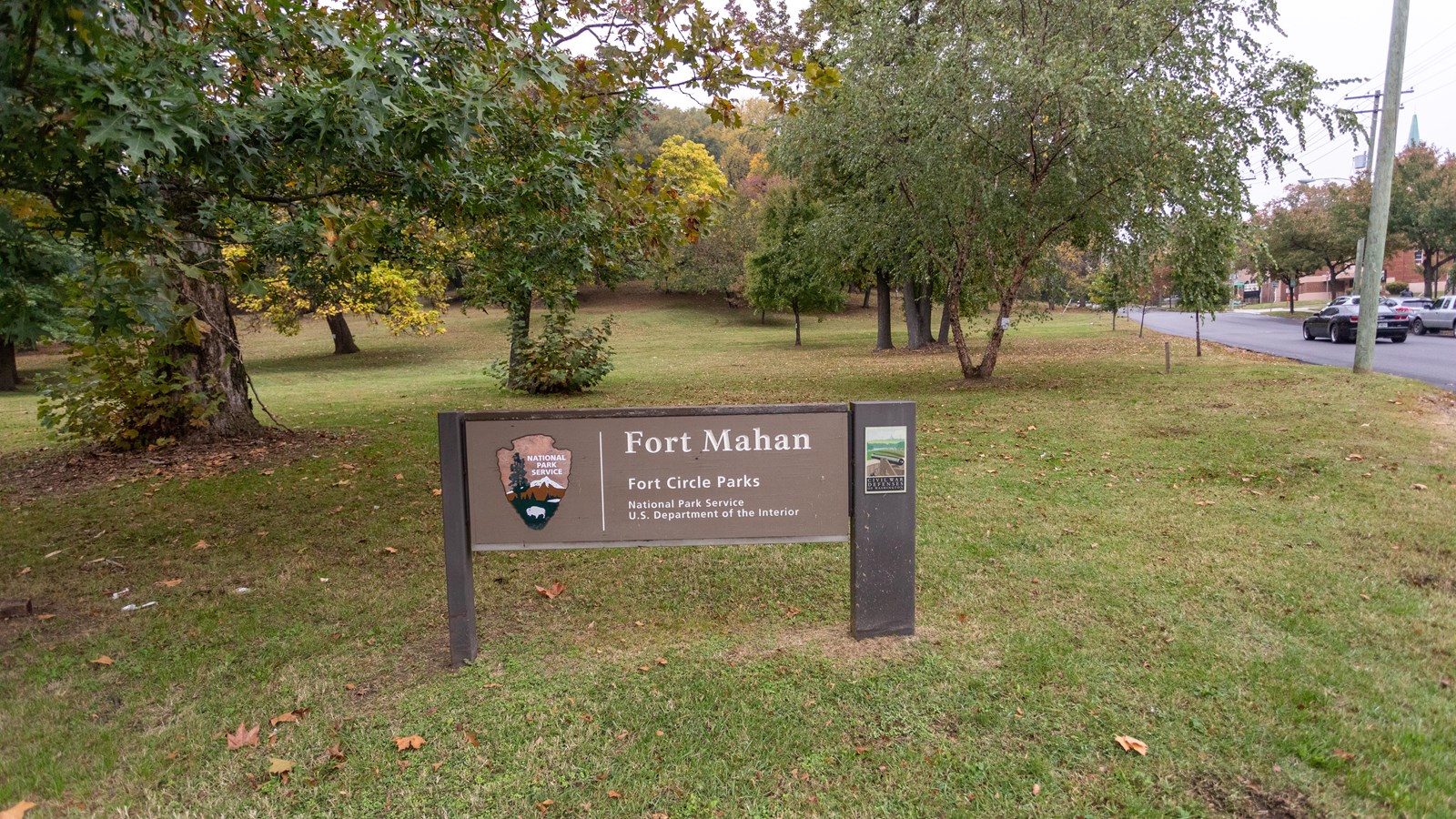 A sign in front of a grassy field