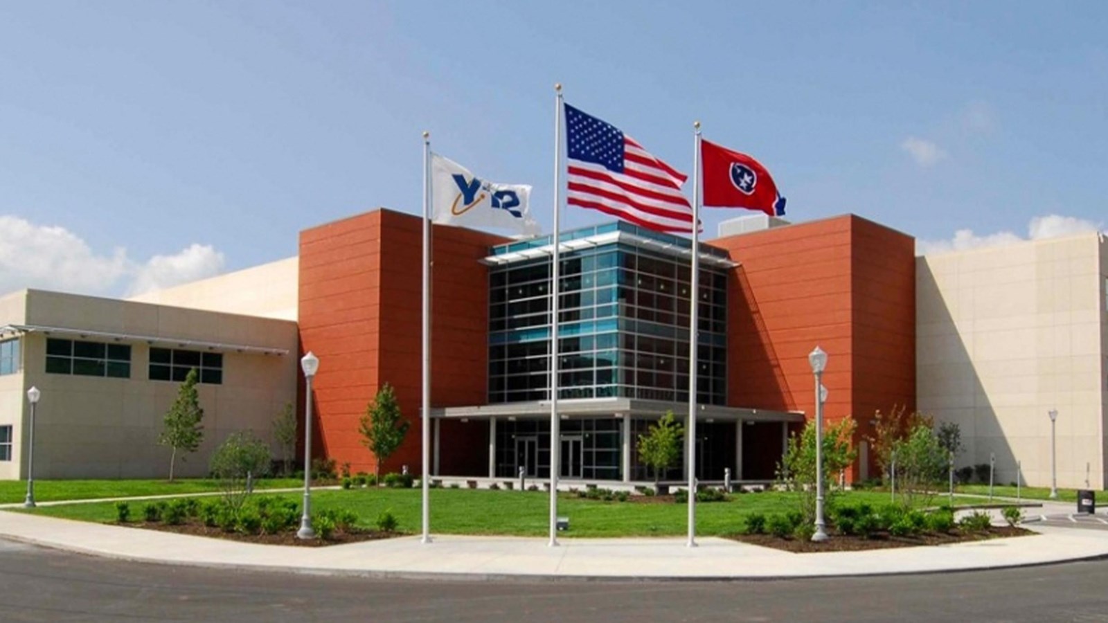 A modern, sunlit office complex with several flags flying in front