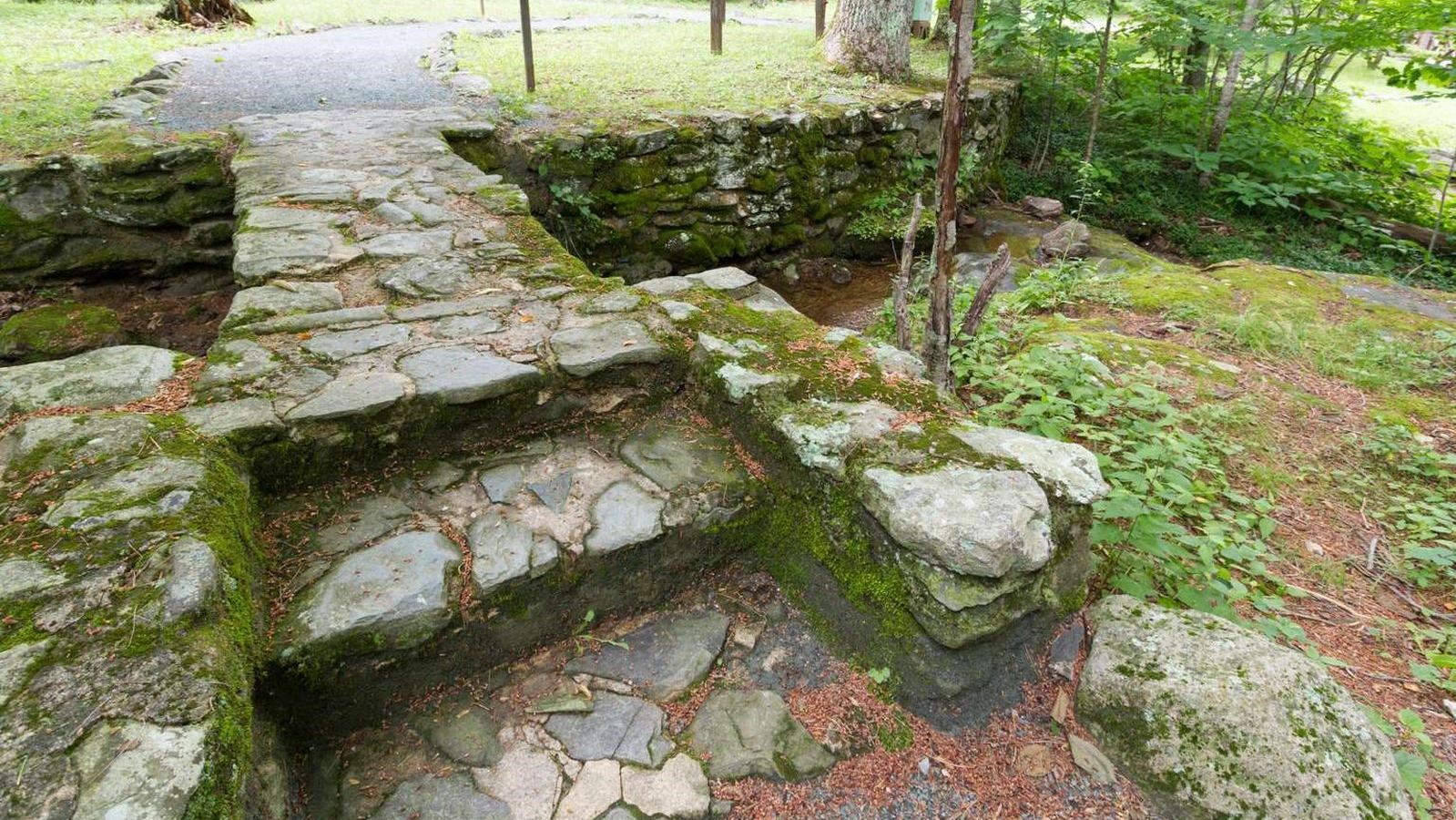 A moss covered bridge made of large stones.