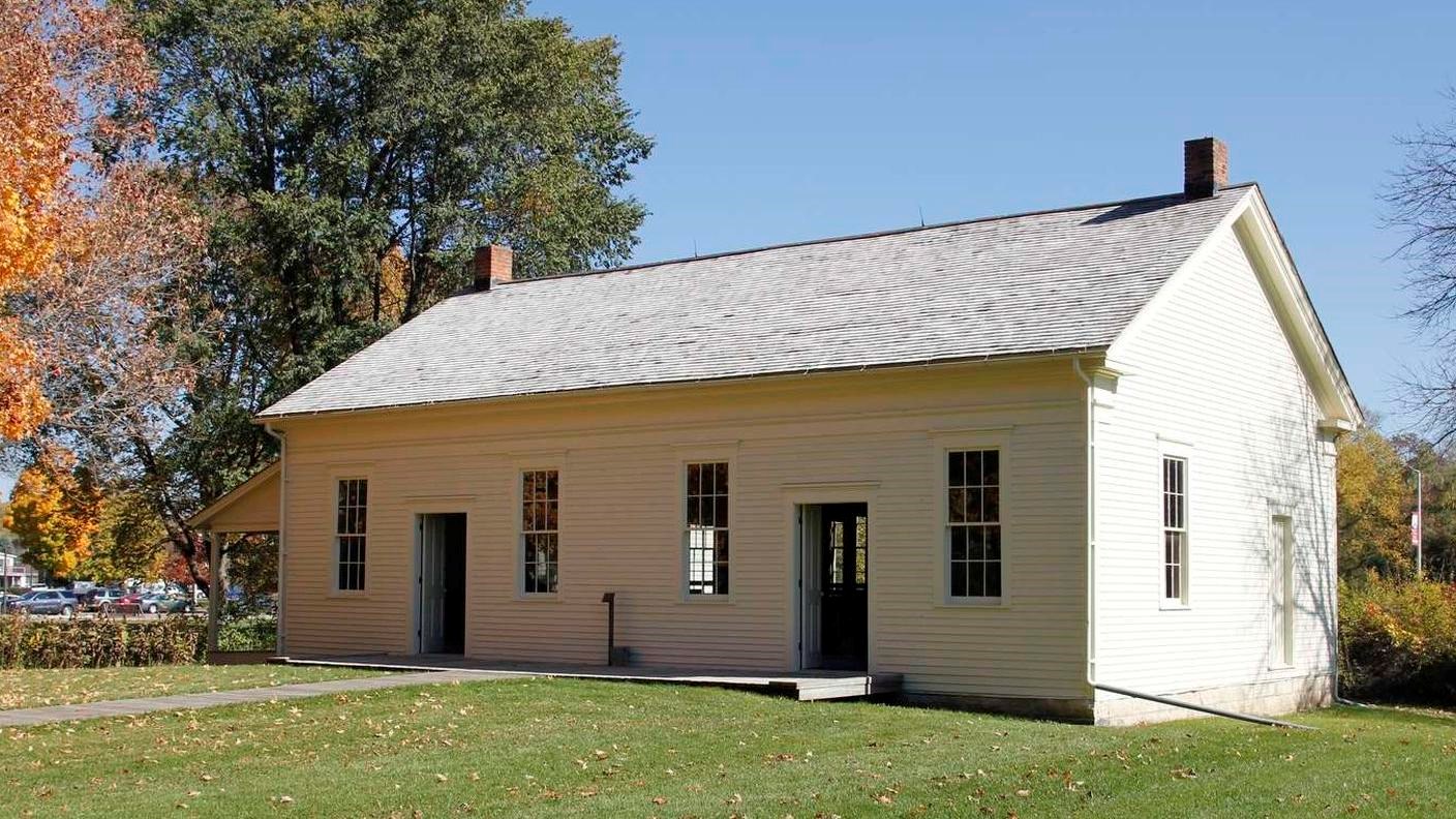 Two doorways, one on either side, of a broad white wood frame building divides the sexes.