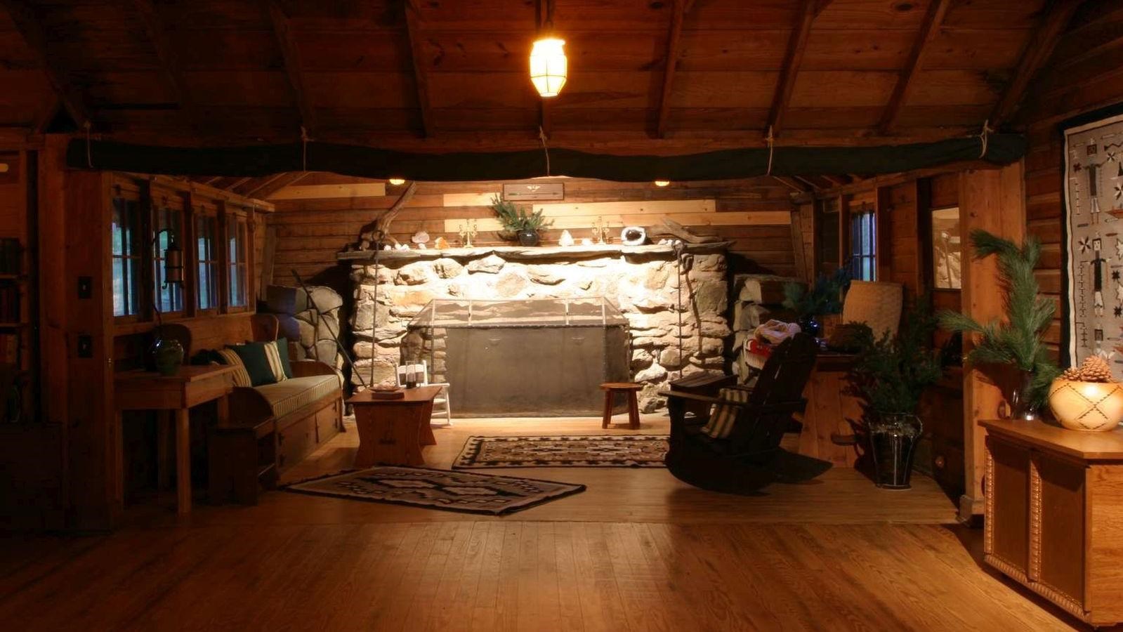 A dimly lit room with a stone fireplace with rustic furniture and Native American wall hangings.