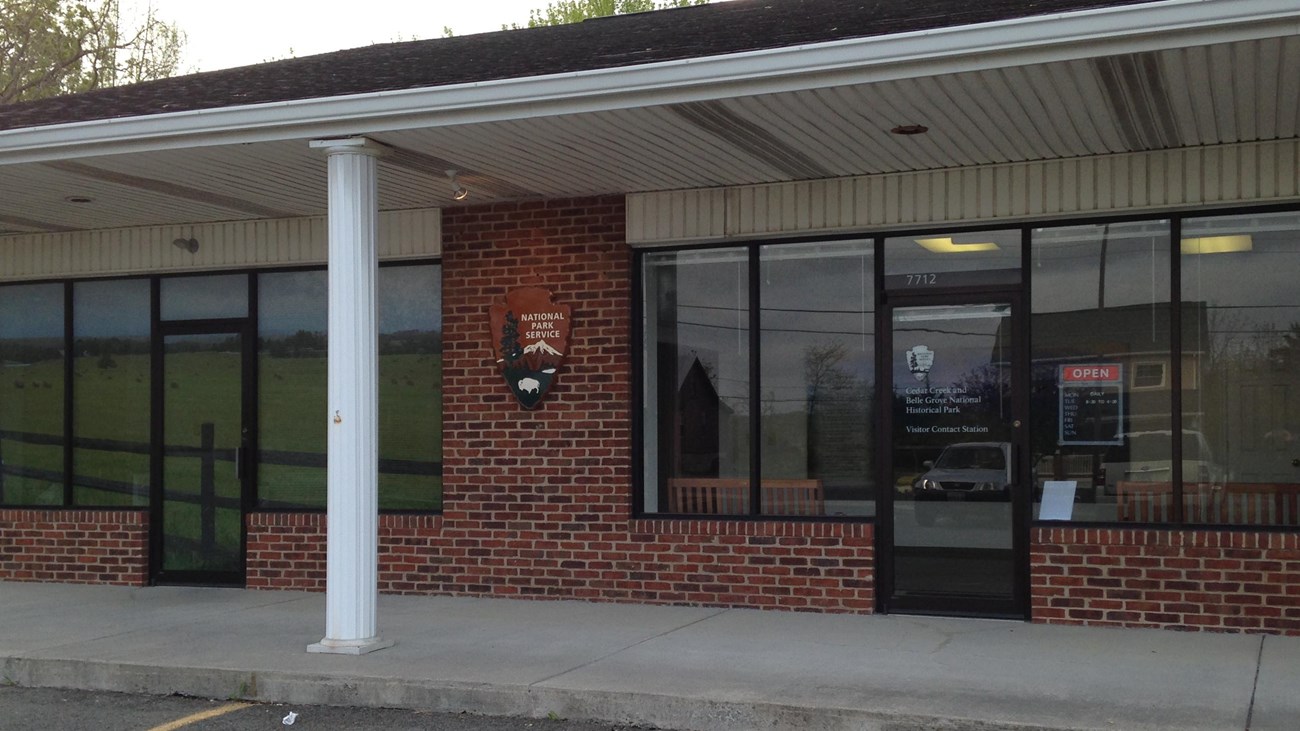 A national park visitor center occupies a store front in a brick commercial building.