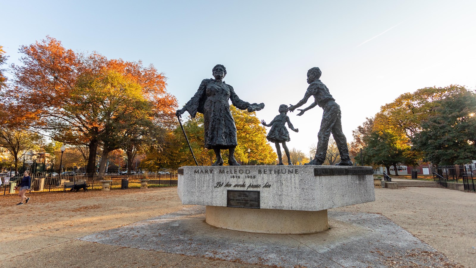 A bronze statue of Mary McLeod handing a paper that represents her legacy to two young children. 
