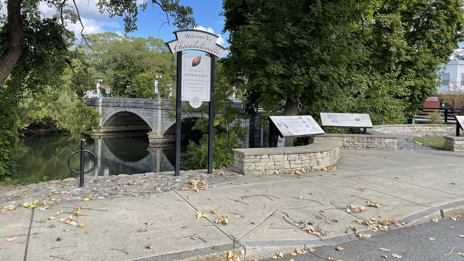 Several white signs with river and bridge in background