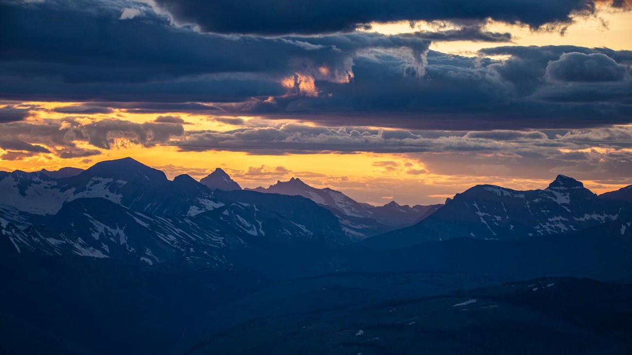 Blue mountains and a golden sunset with clouds