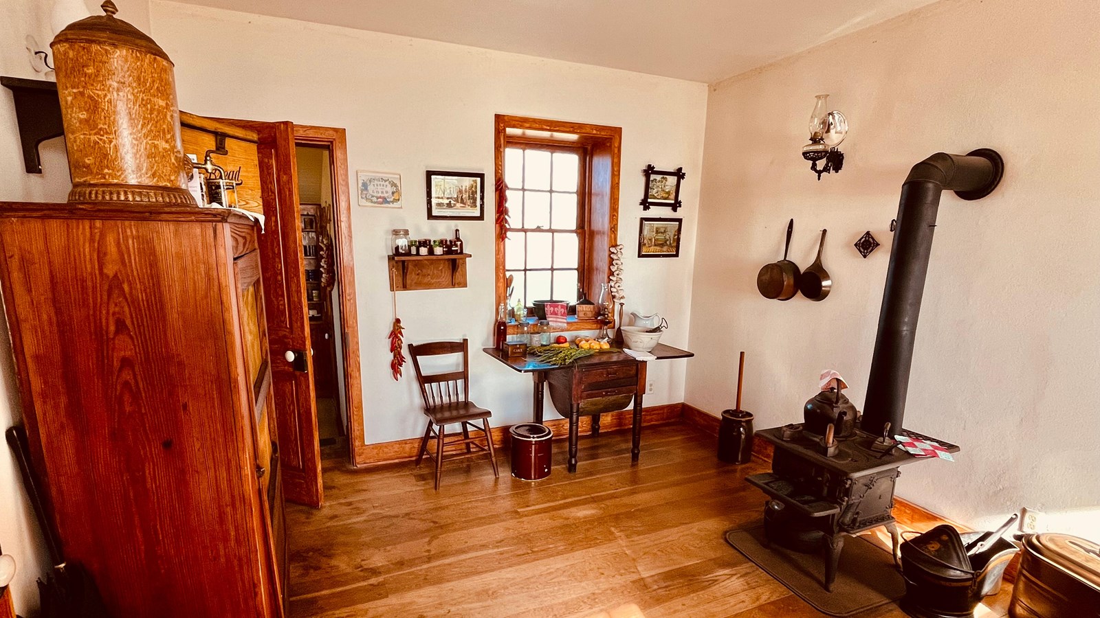A room with wooden floors and white walls, an oven, and a small table.