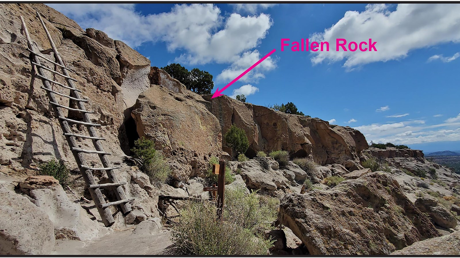 a ladder leans against a cliff with a rock that has obviously separated from the cliff next to it.