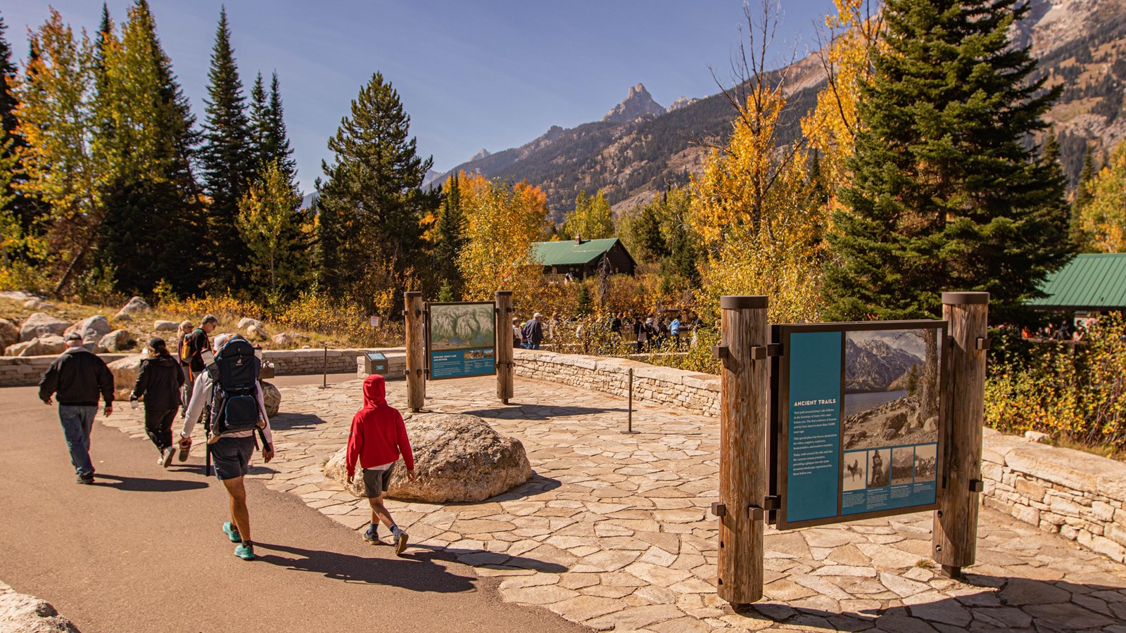 Jenny Lake Trailhead area by the boat desk with informational signs and people walking.