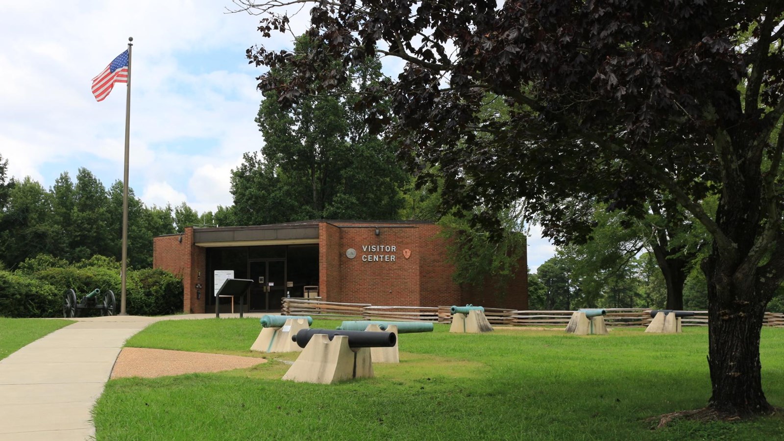 A round brick building, with a U.S. Flag in front. Civil War artillery on display along sidewalks.