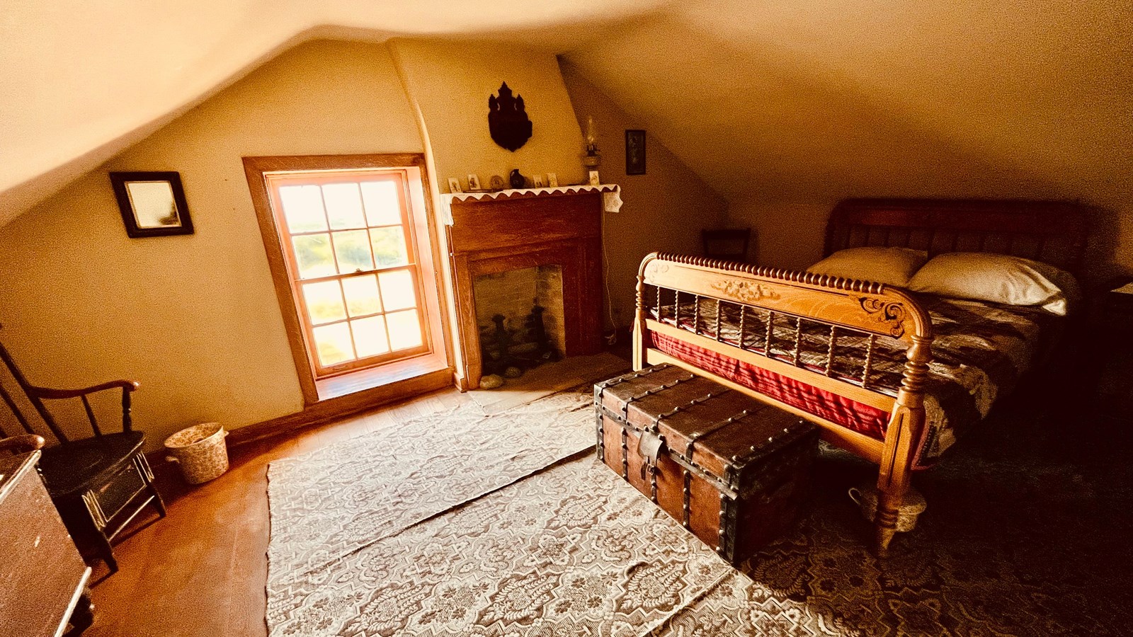A room with a bed, fireplace, large rug and window.